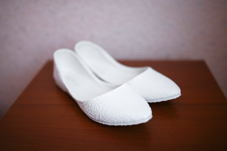 White bride shoes on wooden background, wedding accessoriesの写真素材