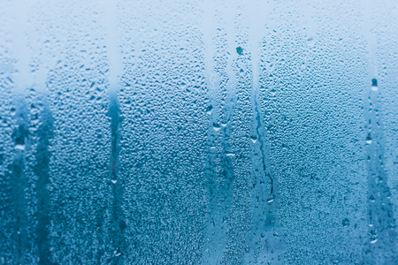 Background of natural water condensation, window glass with high air humidity, large drops drip. Collecting and streaming downの写真素材