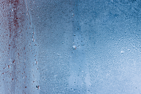 Hot water vapor condensed on the cold window glass, macro texture or backgroundの写真素材