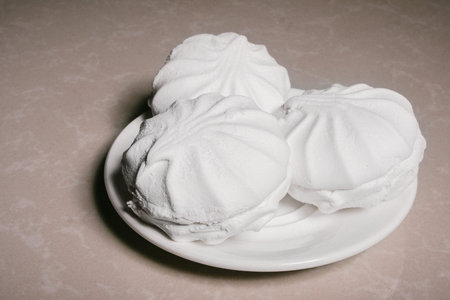 Three delicious sweet dessert white marshmallows zephyr on a saucer close-up. Copy space