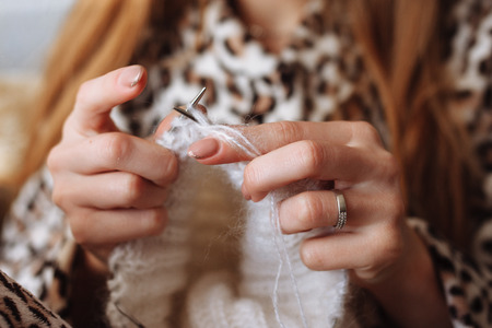 The woman hands knit natural woolen clothes. Knitting needles close-up. Horizontal photo. Freelance creative working. Handcraft conceptの写真素材