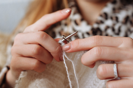 The woman hands knitting woolen clothes. Knitting needles. Close-up. Natural wool. Horizontal photo. Freelance creative working and living conceptの写真素材