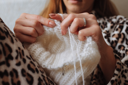The woman hands knit natural woolen clothes. Knitting needles close-up. Horizontal photo. Freelance creative working. Handcraft conceptの写真素材