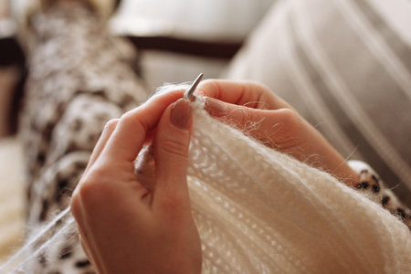 The woman hands knitting woolen clothes. Knitting needles. Close-up. Natural wool. Horizontal photo. Freelance creative working and living conceptの写真素材