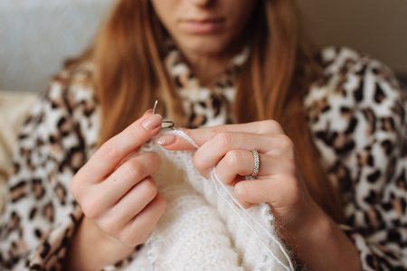 The woman hands knit natural woolen clothes. Knitting needles close-up. Horizontal photo. Freelance creative working. Handcraft conceptの写真素材