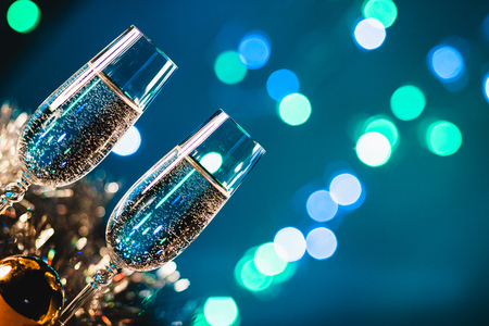 Toasting with champagne glasses against holiday lights and new year fireworksの写真素材