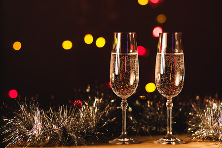 Toasting with champagne glasses against holiday lights and new year fireworksの写真素材