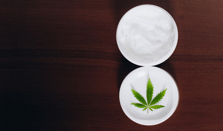 Moisturizing hemp hand cream in dose with green cannabis leaf. Cannabis cosmetics. Cream from biological and ecological plants of hemp vegetable pharmaceutical oil CBDの写真素材