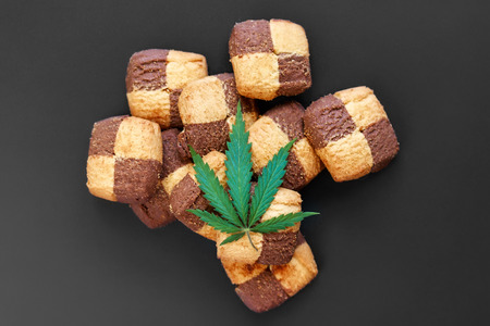 Breakfast with sweet cookies on a dark background with a green leaf of cannabis. Marijuana CBD dessert. Copy space. View from above. Concept of marijuana use for medicinal purposesの写真素材