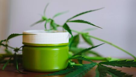 Cannabis hemp cream background with marijuana leaf - cannabis concept self care in of health care. Cosmetics with hemp extract on table. Herbal organic medicine CBD productの写真素材