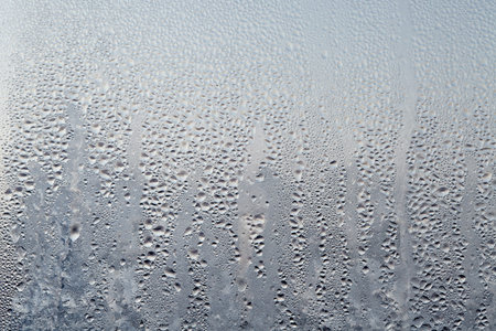 Frozen drops of condensed steam water drops on the transparent window glass. Clean background....