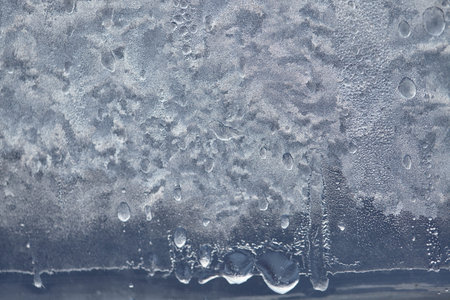 Texture of Frozen drops of condensed steam water drops on the transparent window glass. Clean...