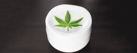 Organic natural cannabis cream leaf CBD panorama with copy space for your design or text on dark background. Concept of herbal alternative medicine, CBD. Jar of ecological hemp white lotionの写真素材