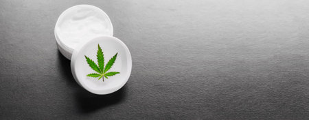Jar with hemp lotion, cannabis cream with hemp leaf with dark copy space. Natural product, cosmetic cannabis cream from natural hemp, moisturizing lotion with CBD contentの写真素材