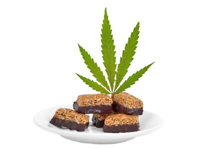 Candy with the addition of medical cannabis CBD for recreational use to relax body and mind. Sweet cannabis candy CBD Cannabidiol next to green leaves of marijuana on white isolated backgroundの写真素材