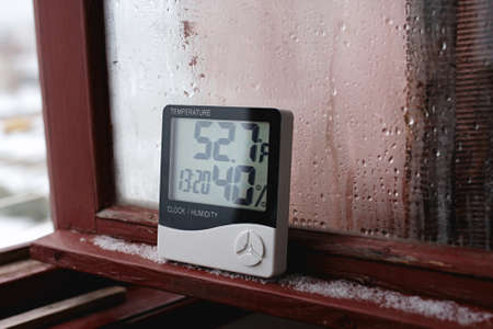 Measurement of air temperature, dew point, humidity with a device (hygrometer), against a background with condensation on the glass, high humidityの写真素材