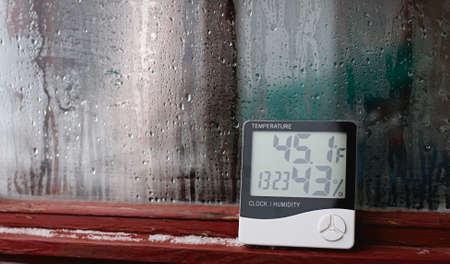 Measurement of air temperature, dew point, humidity with a device (hygrometer), against a background with condensation on the glass, high humidityの写真素材