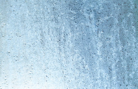 Frozen drops of condensation on a window, a sharp drop in temperature, sharply frozen drops of water on glass in winter, extremely cold low air temperaturesの写真素材