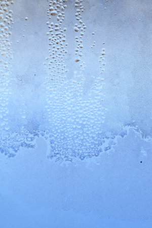 Natural frozen drops of condensation on transparent glass. Beautiful background from a frozen window in winter. Drops texture on the glassの写真素材