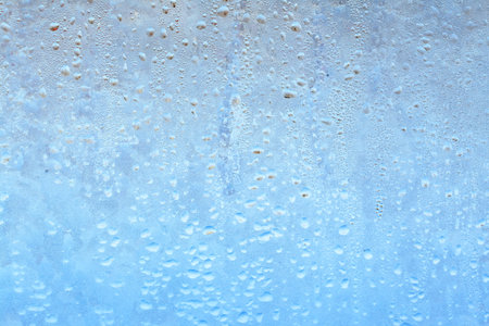 Natural frozen drops of condensation on transparent glass. Beautiful background from a frozen window in winter. Drops texture on the glassの写真素材