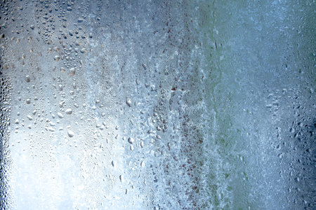 Natural frozen drops of condensation on transparent glass. Beautiful background from a frozen window in winter. Drops texture on the glassの写真素材