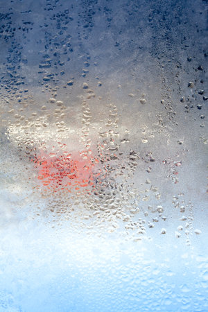 Frozen drops of condensation on a window, a sharp drop in temperature, sharply frozen drops of water on glass in winter, extremely cold low air temperaturesの写真素材