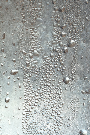Frozen drops of condensation on a window, a sharp drop in temperature, sharply frozen drops of water on glass in winter, extremely cold low air temperaturesの写真素材