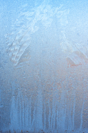 Beautiful natural background or texture of frozen transparent glass on the window in winter, extreme cold concept, vertical image, copy space for your design or textの写真素材