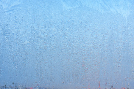 Completely frozen window on transparent glass. Clean background. Extreme low temperatures in winter. Water vapor condenses on cold window glass and freezesの写真素材