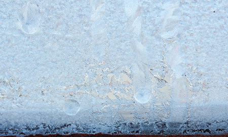 Completely frozen window on transparent glass. Clean background. Extreme low temperatures in winter. Water vapor condenses on cold window glass and freezesの写真素材