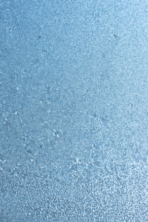 Vertical image of a winter background on a transparent glass window with a frozen texture. Abstract texture background, vertical photo, copy space for your design or textの写真素材