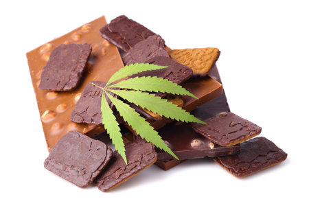 Bars of black and milk chocolate with cookies containing CBD cannabis and green hemp leaf on white isolated background. Chocolate with marijuana extract. Entertainment drug conceptの写真素材