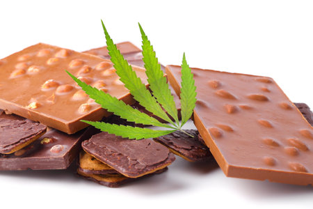 Chocolate with marijuana extract, chocolate biscuits with CBD content. Entertainment drugs concept. Chocolate bars with nuts and CBD cannabis content, green hemp leaf on white isolated background.の写真素材