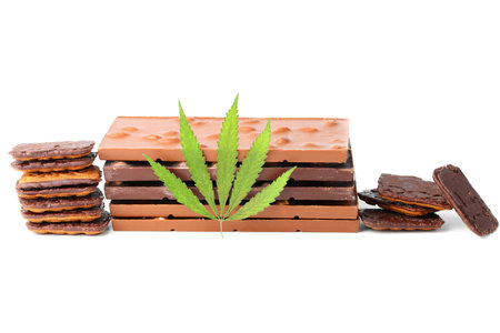 Edible medical marijuana food chocolate bars and chocolate cookies with green hemp leaf isolated on white background. Cannabis chocolates CBDの写真素材