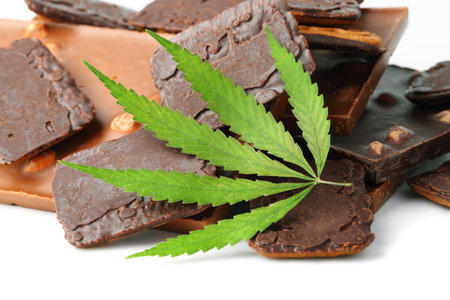 Chocolate bars and biscuits close-up with hemp leaf on white isolated background. Chocolate marijuana dessert cookies with CBD cannabisの写真素材