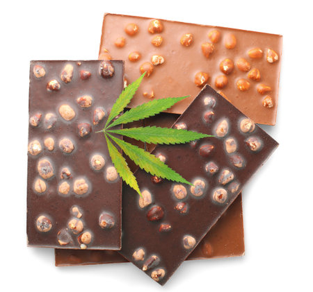 Delicious chocolate bars with nuts and green hemp leaves, chocolate containing CBD cannabis, isolated white backgroundの写真素材