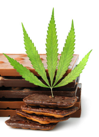 Chocolate bars and biscuits close-up with hemp leaf on white isolated background. Chocolate marijuana dessert cookies with CBD cannabisの写真素材