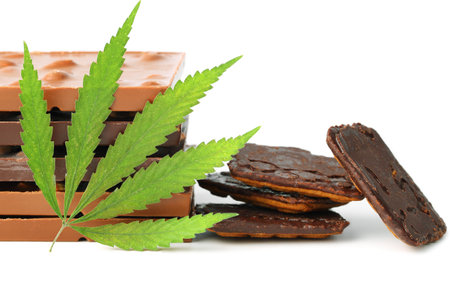 Edible medical marijuana food chocolate bars and chocolate cookies with green hemp leaf isolated on white background. Cannabis chocolates CBDの写真素材