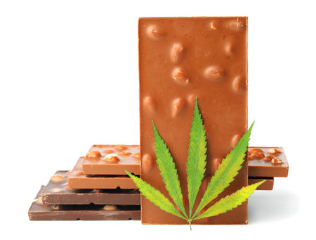 Edible medical marijuana food chocolate bars and chocolate cookies with green hemp leaf isolated on white background. Cannabis chocolates CBDの写真素材