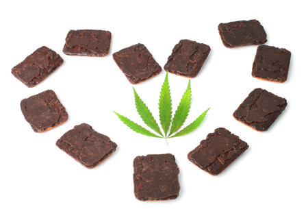 Green marijuana leaf in the middle of a heart made of chocolate biscuits which contain cannabis extract CBD on white isolated backgroundの写真素材