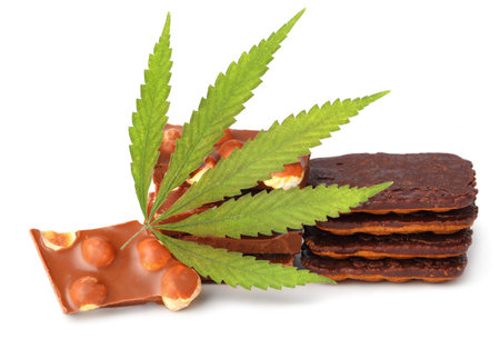 Edible medical marijuana food chocolate bars and chocolate cookies with green hemp leaf isolated on white background. Cannabis chocolates CBDの写真素材