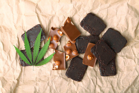 Pieces of chocolate with cannabis CBD nuts with dry green hemp leaf. Hemp biscuits covered with chocolate glaze. Marijuana sweet food conceptの写真素材
