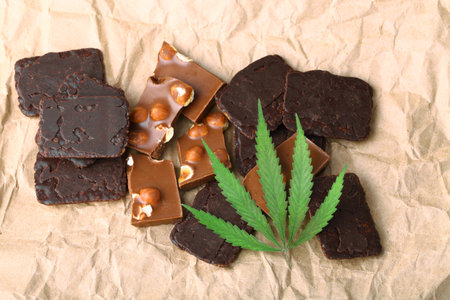 Pieces of chocolate with cannabis CBD nuts with dry green hemp leaf. Hemp biscuits covered with chocolate glaze. Marijuana sweet food conceptの写真素材