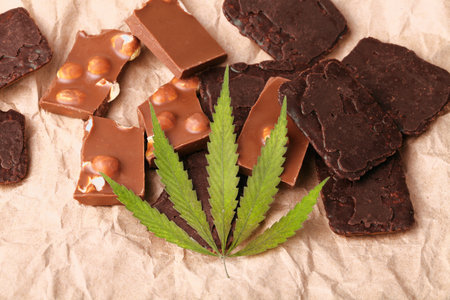 Organic Marijuana Pieces of Chocolate with CBD cannabis nuts and dry green hemp leaves. Chocolate coated hemp biscuits. Marijuana sweet food conceptの写真素材