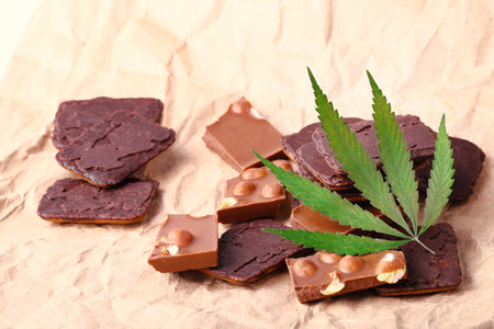 Organic Marijuana Pieces of Chocolate with CBD cannabis nuts and dry green hemp leaves. Chocolate coated hemp biscuits. Marijuana sweet food conceptの写真素材