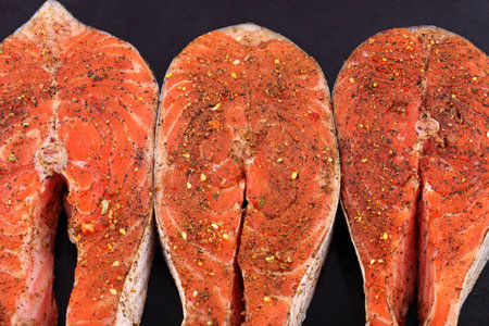 Fresh raw salmon steaks with spices on a black backgroundの写真素材