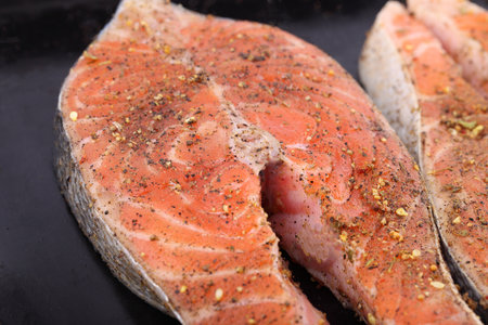 Fresh raw salmon steaks with spices on a black backgroundの写真素材