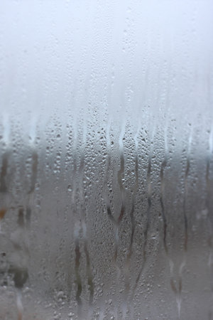 Background of natural condensation of water on transparent glass with high air humidity, large drops drippingの写真素材