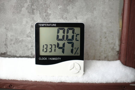 Digital thermometer on a window with snow on the background of frozen glass. Electronic thermometer and hygrometer for temperature and humidity controlの写真素材