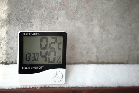 Digital thermometer on a window with snow on the background of frozen glass. Electronic thermometer and hygrometer for temperature and humidity controlの写真素材
